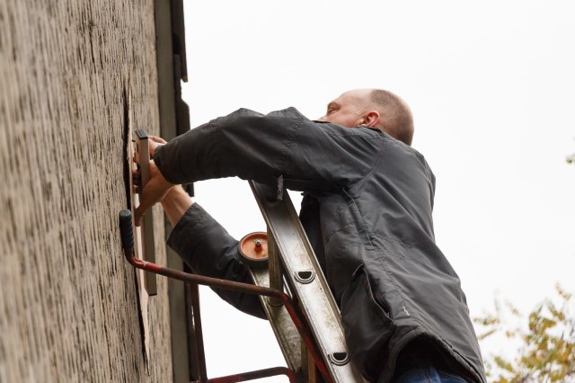 Ruud PE1POA op een ladder met afstandshouder. Ik had een boormal gemaakt van karton, dus eerst moest er afgetekend worden.